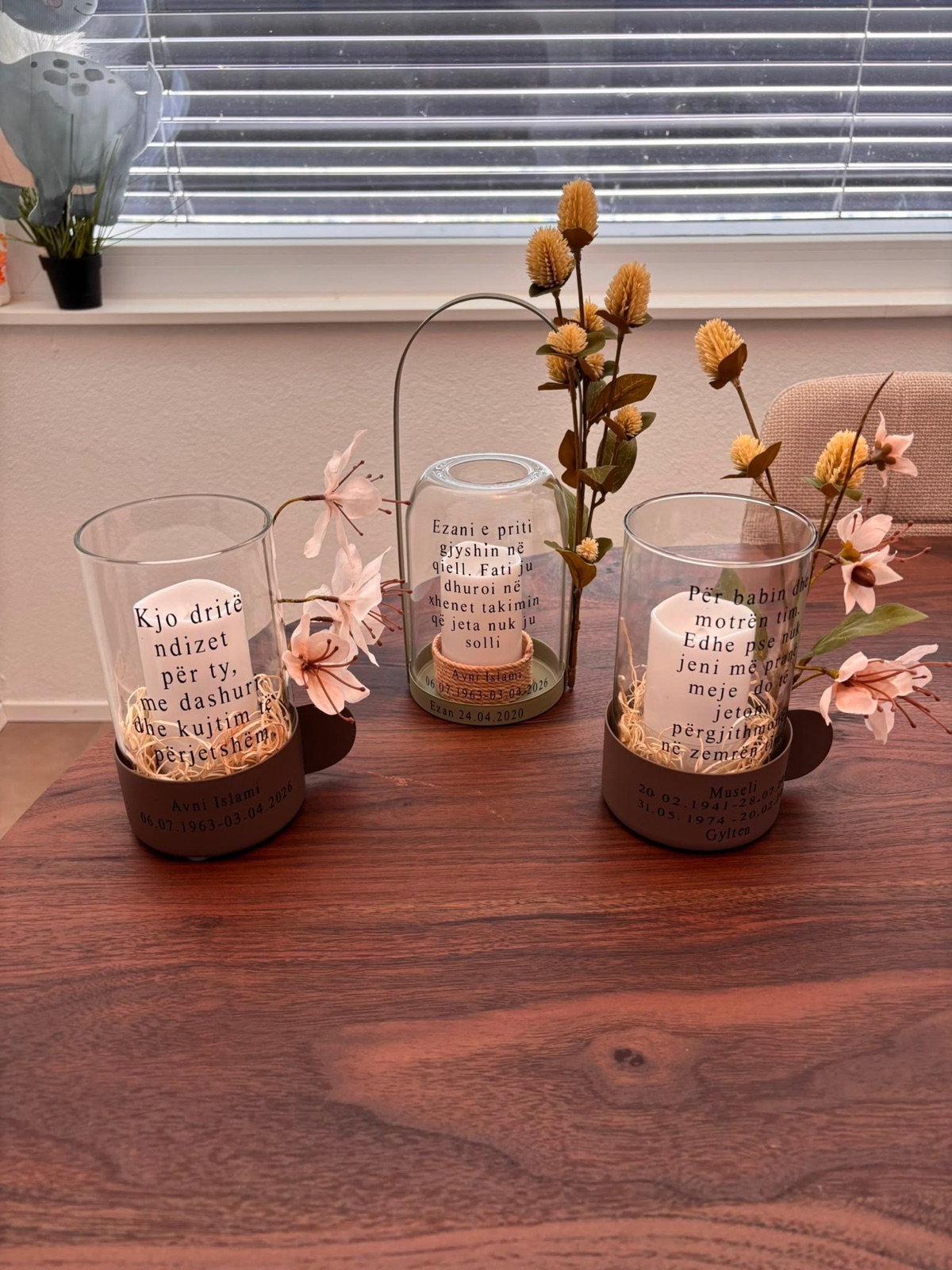 Drei gravierte Kerzenlaternen mit Trockenblumen auf einem Holztisch